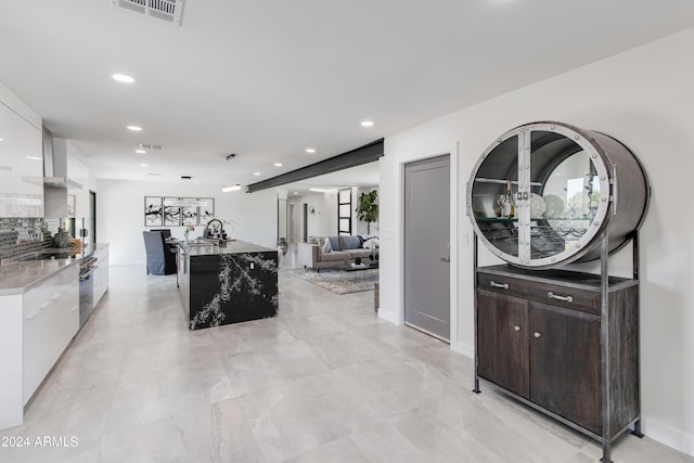 kitchen featuring light tile flooring, a kitchen island, stone countertops, wall chimney exhaust hood, and dark brown cabinets