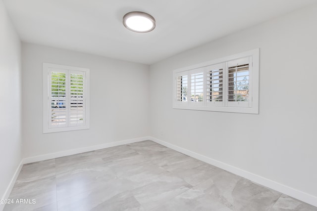 spare room with a wealth of natural light and light tile floors