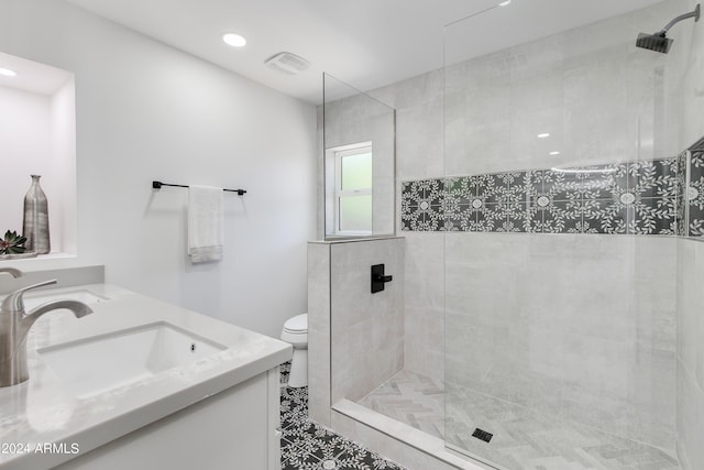 bathroom with a tile shower, tile floors, toilet, and dual bowl vanity