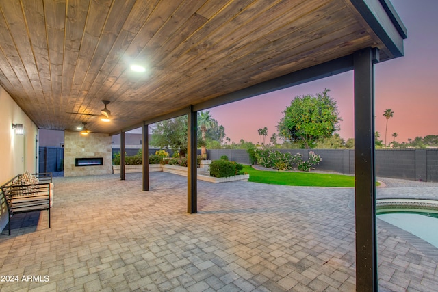 patio terrace at dusk with ceiling fan and a fenced in pool