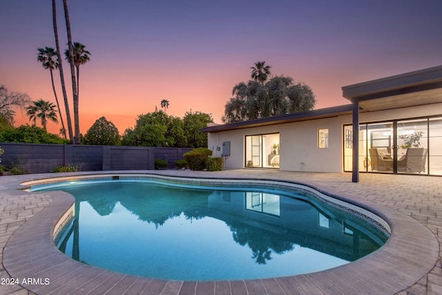 pool at dusk with a patio area