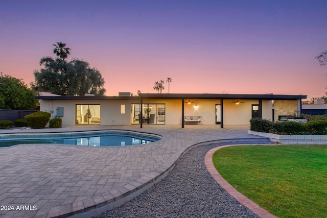 pool at dusk featuring a patio and a yard