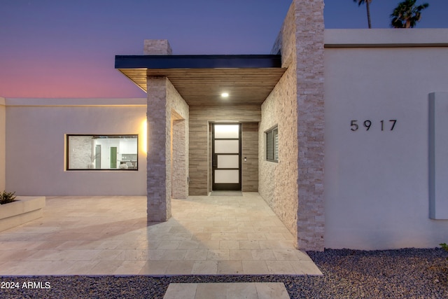 exterior entry at dusk featuring a patio area