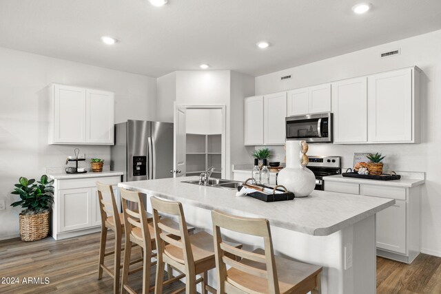 kitchen featuring white cabinets, a kitchen breakfast bar, sink, an island with sink, and appliances with stainless steel finishes