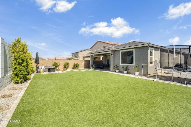17976 W Ashley Dr, Goodyear, AZ 85338 - back of property featuring a trampoline, a patio, a fenced backyard, stucco siding, and a tiled roof