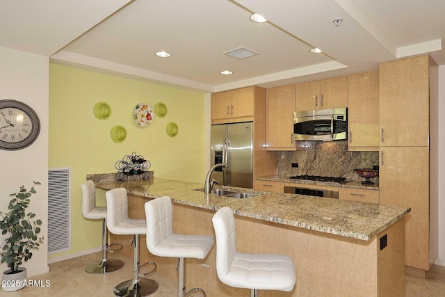 kitchen with visible vents, backsplash, appliances with stainless steel finishes, a sink, and a peninsula