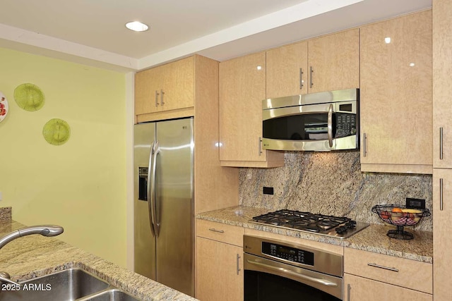 kitchen with stainless steel appliances, backsplash, and light brown cabinetry