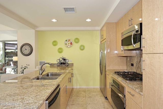 kitchen featuring tasteful backsplash, visible vents, light stone counters, stainless steel appliances, and a sink