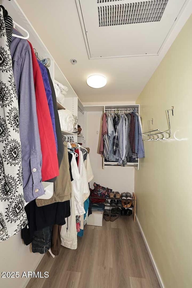 spacious closet with attic access, visible vents, and wood finished floors