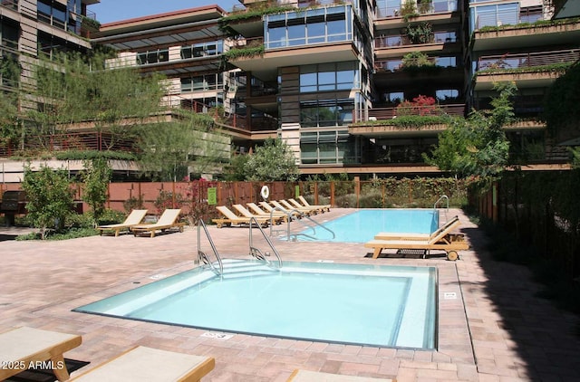 pool with a community hot tub, a patio area, and fence