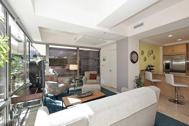 living area with a wall of windows, visible vents, and recessed lighting