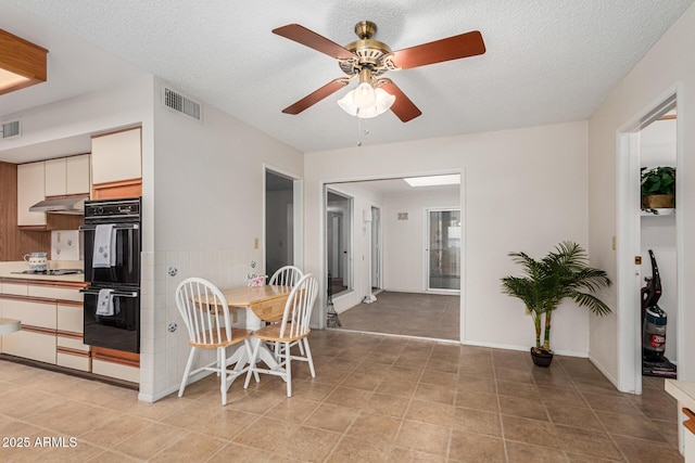 dining room with a ceiling fan, visible vents, a textured ceiling, and light tile patterned floors