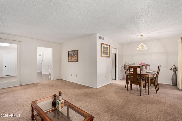 carpeted dining room featuring a chandelier, a textured ceiling, and visible vents