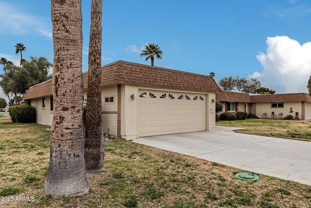 view of front of home featuring a shingled roof, mansard roof, concrete driveway, an attached garage, and a front lawn