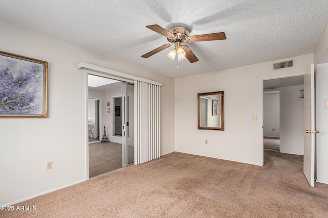 unfurnished bedroom with a ceiling fan, carpet, visible vents, and a textured ceiling