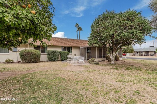 ranch-style house with a sunroom, a patio area, a front lawn, and roof with shingles