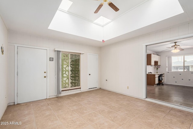 interior space with a skylight, light tile patterned flooring, and ceiling fan