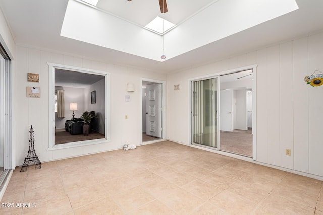 spare room with a skylight, light tile patterned flooring, and ceiling fan