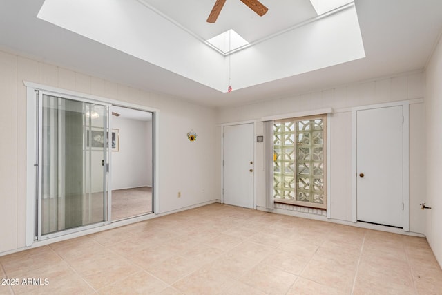 unfurnished room featuring light tile patterned floors, a skylight, and a ceiling fan