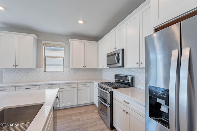 kitchen with stainless steel appliances, white cabinetry, light wood finished floors, decorative backsplash, and recessed lighting