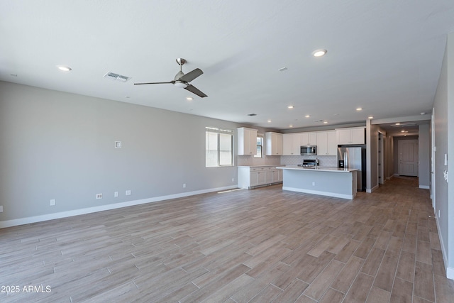 unfurnished living room featuring light wood-style flooring, ceiling fan, baseboards, and recessed lighting