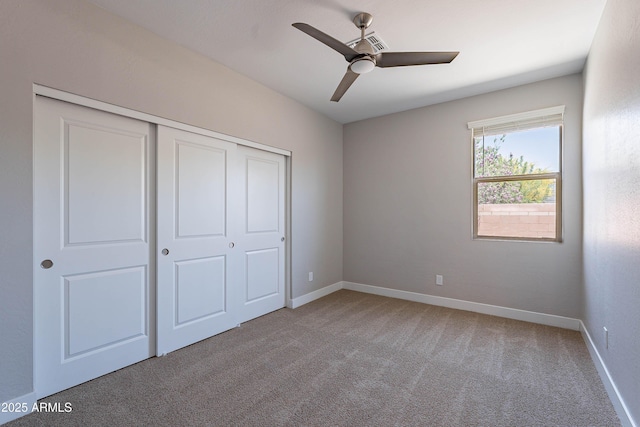 unfurnished bedroom featuring a closet, carpet, baseboards, and ceiling fan