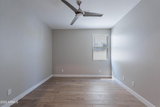 unfurnished room with a ceiling fan, wood finished floors, and baseboards