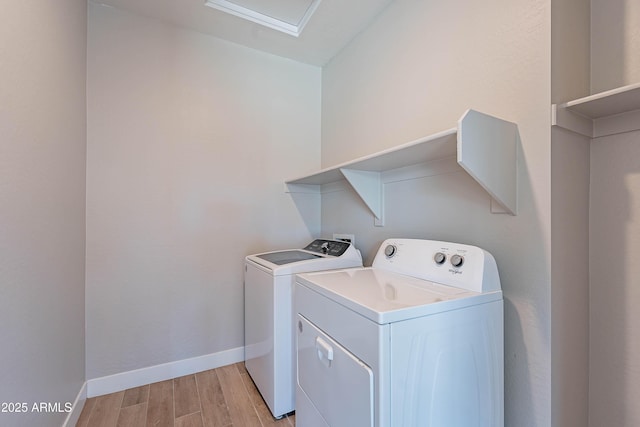 laundry room featuring independent washer and dryer, light wood-style flooring, and baseboards