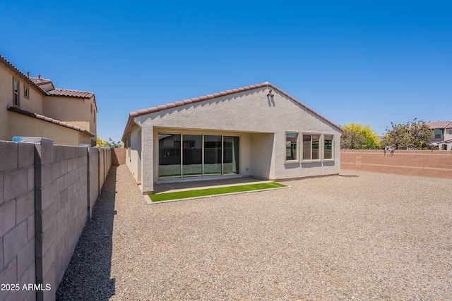 back of house featuring stucco siding, a fenced backyard, a tile roof, and a patio