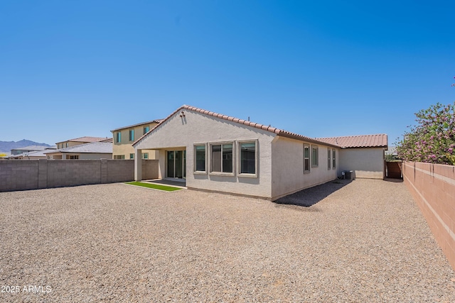 back of house featuring a tiled roof, stucco siding, and a fenced backyard
