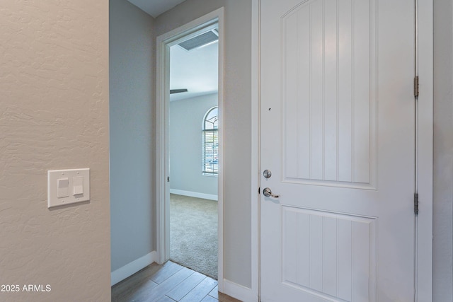 entryway featuring a textured wall, baseboards, and wood finished floors