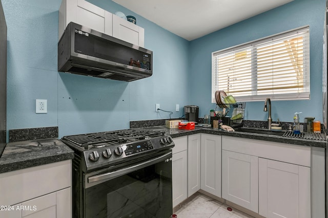 kitchen with gas range, sink, dark stone countertops, and white cabinets