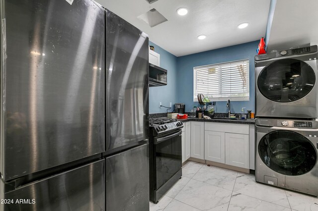 laundry room with stacked washer and dryer, sink, and light tile patterned floors