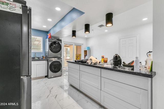 laundry area featuring stacked washing maching and dryer and sink