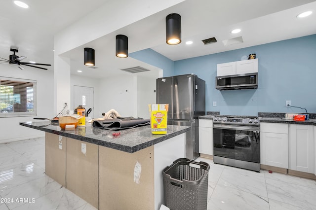 kitchen featuring dark stone countertops, appliances with stainless steel finishes, a kitchen island, ceiling fan, and white cabinets