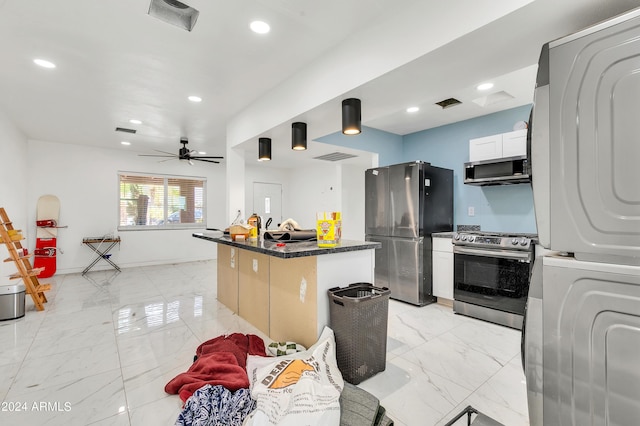 kitchen with stacked washing maching and dryer, appliances with stainless steel finishes, white cabinetry, a center island, and ceiling fan