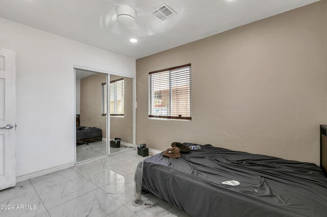 tiled bedroom with ceiling fan and a closet