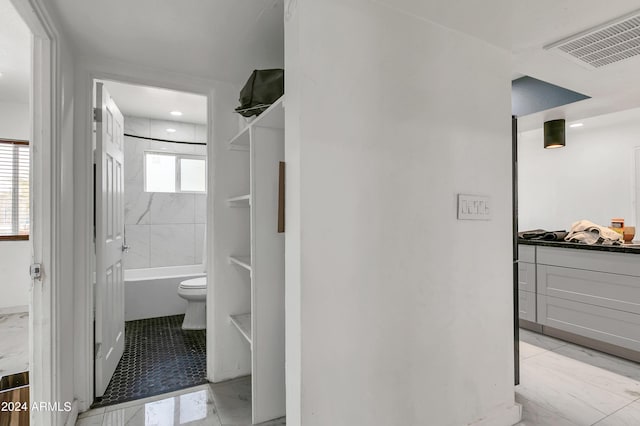 bathroom featuring tiled shower / bath combo and toilet