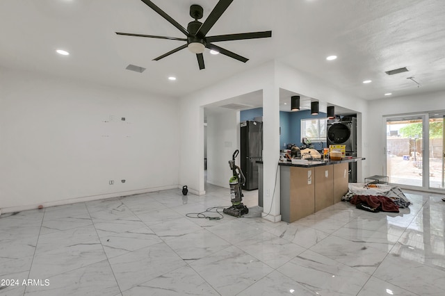 kitchen with stacked washer / drying machine, ceiling fan, black fridge, and light tile patterned floors