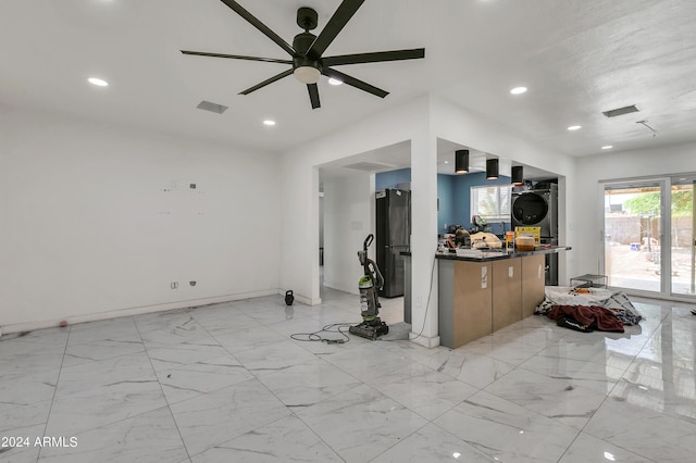 kitchen with black refrigerator, ceiling fan, and stacked washer and clothes dryer