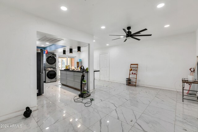 interior space with ceiling fan and stacked washer / dryer