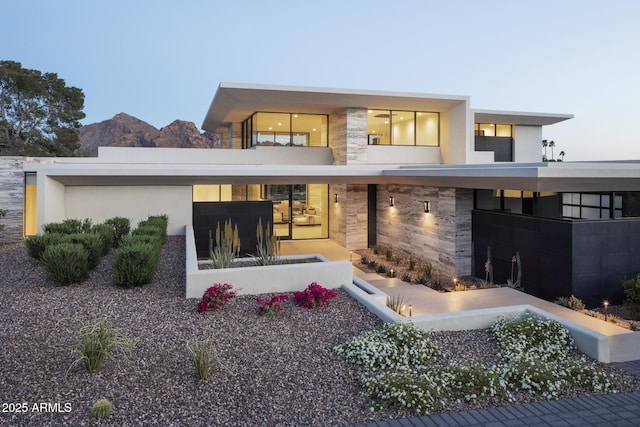 back house at dusk with a mountain view and a balcony