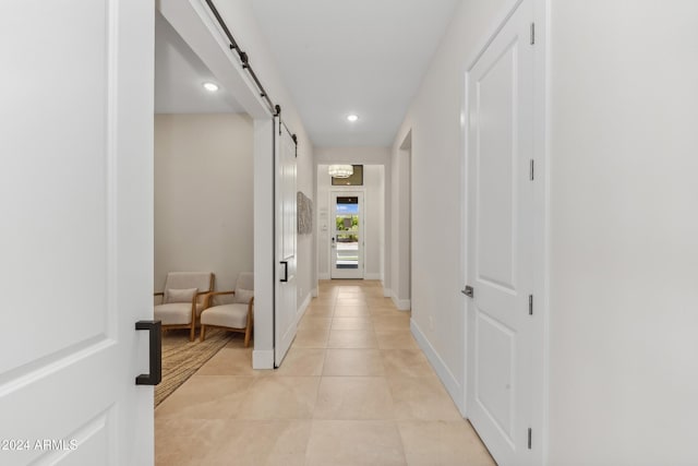 corridor featuring light tile patterned floors and a barn door