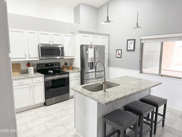 kitchen featuring sink, appliances with stainless steel finishes, pendant lighting, light stone countertops, and white cabinets