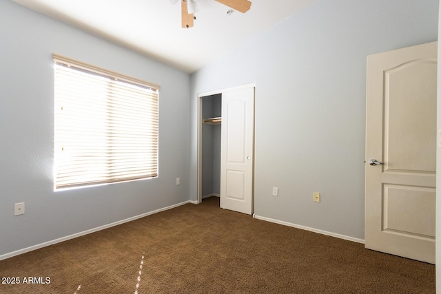 unfurnished bedroom with dark carpet, a closet, vaulted ceiling, and ceiling fan