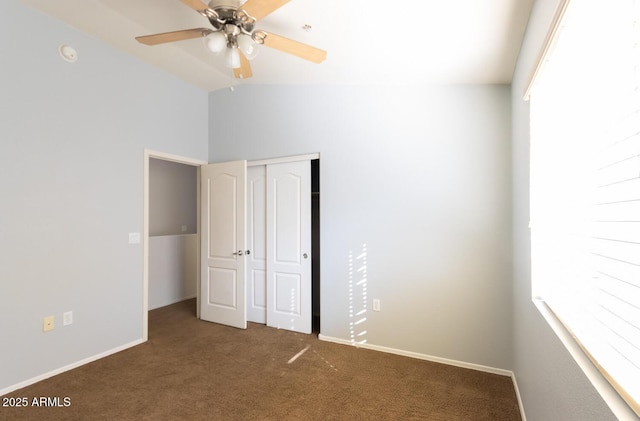 unfurnished bedroom with ceiling fan, a closet, and dark colored carpet