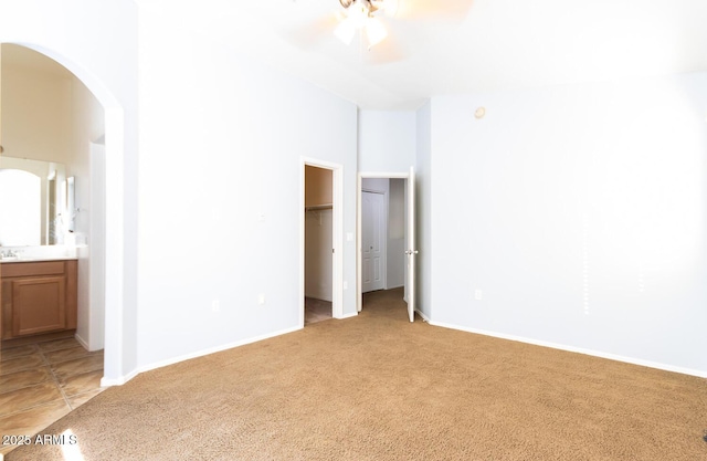 unfurnished room featuring a towering ceiling, ceiling fan, and light colored carpet