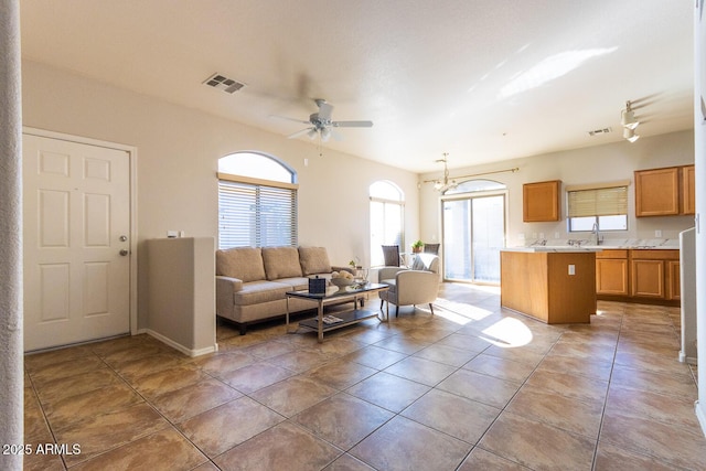 tiled living room with ceiling fan with notable chandelier