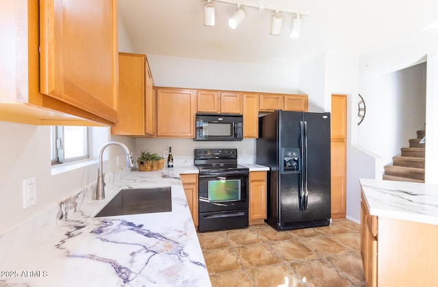 kitchen featuring black appliances, light stone countertops, and sink