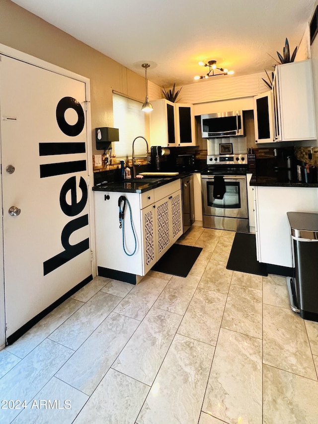 kitchen with dark countertops, white cabinetry, appliances with stainless steel finishes, and a sink